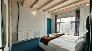 a bedroom with a bed and a large window at ApriQuince Lodge in Tangmarg