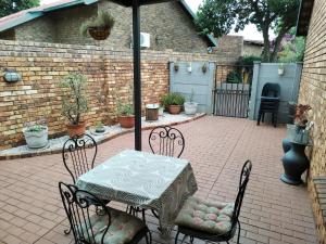 eine Terrasse mit einem Tisch mit Stühlen und einem Sonnenschirm in der Unterkunft Jan's Cottage in Centurion