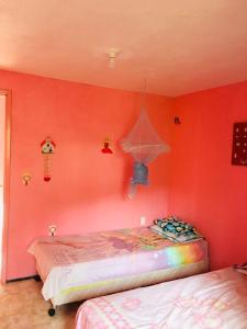 a bedroom with red walls and two beds in it at Casa da Barbie da Serra in Pacoti