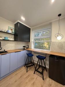a kitchen with two blue bar stools and a counter at Уютная и стильная квартира в центре города Караганда in Karagandy