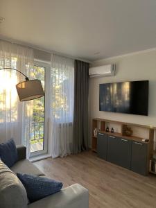 a living room with a couch and a large window at Уютная и стильная квартира в центре города Караганда in Karagandy