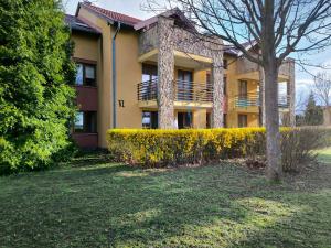 a yellow building with a tree in front of it at Sunset Green Apartman in Bük