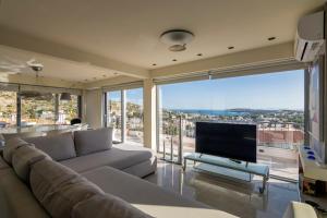 a living room with a couch and a tv at Breathtaking Penthouse Vouliagmeni in Athens