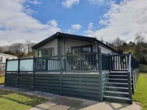 a tiny house with a porch and a deck at Llanrhidian Holiday Park in Llanmorlais
