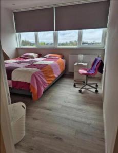 a bedroom with a bed and a chair and a window at Sfeervol huis nabij het centrum van Harlingen in Harlingen