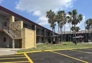a parking lot in front of a building with palm trees at Red Roof Inn Corpus Christi North - Near Downtown in Corpus Christi