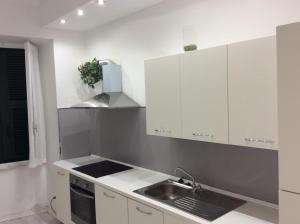 a kitchen with white cabinets and a sink at Bella Vernazza with AC and Balcony in Vernazza