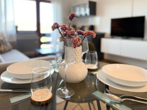 une table avec des assiettes et des verres et un vase avec des fleurs dans l'établissement Schwarzwald Apartment mit Weitblick - Villa Hubertus, à Feldberg