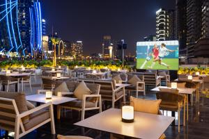 a restaurant with tables and chairs and a large screen at Royal Continental Suites Business Bay - Deluxe Apartments in Dubai