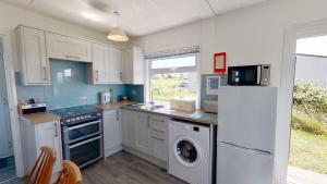 a kitchen with white cabinets and a washer and dryer at B44 Sea Urchin, Riviere Towans in Hayle +16 photos