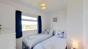 two beds in a small room with a window at B44 Sea Urchin, Riviere Towans in Hayle