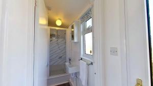 a white bathroom with a sink and a window at B44 Sea Urchin, Riviere Towans in Hayle