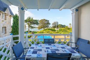 Un patio con una mesa y sillas en un balcón. en Les Mousses - Superbe vue mer, en Bénodet