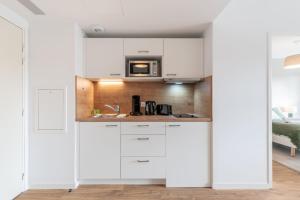 una cucina con mobili bianchi e un forno a microonde di OVELIA Saint-Saulve - Les Quatre Jardins a Saint-Saulve Altre 5 foto