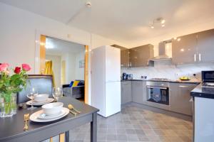 une cuisine avec une table et un réfrigérateur blanc dans l'établissement Manchester Townhouse by BEVOLVE - 4 bedrooms - Free Parking, à Manchester