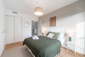 una camera da letto con un letto grande con una coperta verde di OVELIA Saint-Saulve - Les Quatre Jardins a Saint-Saulve