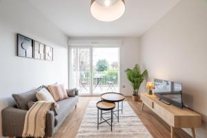 un soggiorno con un divano, una TV e un tavolo di OVELIA Saint-Saulve - Les Quatre Jardins a Saint-Saulve