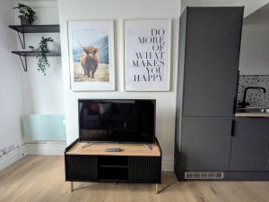 a living room with a television and posters on the wall at Conegra Road Apartments in High Wycombe +3 photos