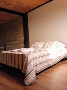 a bed with a striped blanket on a wooden floor at ALMA Posada in Almafuerte +13 photos