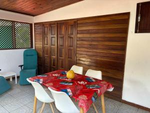 La Maison de Marie, 2 chambres, spacieuse et confortable في سانت لويس: غرفة طعام مع طاولة مع كراسي بيضاء وقطعة قماش طاولة حمراء