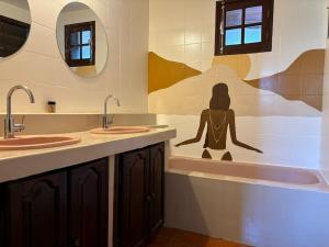 La Maison de Marie, 2 chambres, spacieuse et confortable في سانت لويس: حمام به مغسلتين وحوض استحمام مع رجل على الحائط