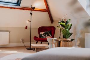 a living room with a red chair and a lamp at Jacques van Marken Erfgoed in Delft