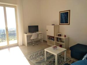 a living room with a tv and a desk with a chair at La Valle di Rosa in Agrigento
