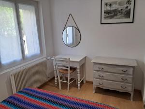 a bedroom with a desk and a mirror and a dresser at 2 Chambres d'hôtes Chante-Coucou in Onet le Château +6 photos