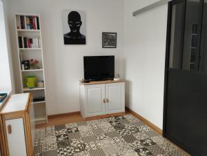 a living room with a flat screen tv on a cabinet at 2 Chambres d'hôtes Chante-Coucou in Onet le Château