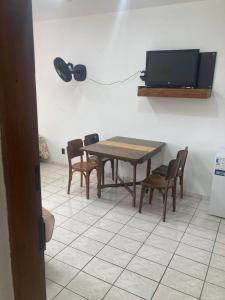 Un comedor con mesa y sillas y un televisor. en Sunset House Caraguatatuba S, en Caraguatatuba