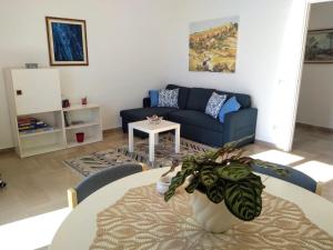 a living room with a table and a blue couch at La Valle di Rosa in Agrigento