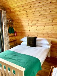 a bed in a room with a wooden wall at Cedar Pod, Clay Bank Huts in Middlesbrough