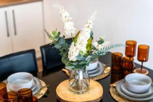 een tafel met een vaas met witte bloemen erin bij Luxury 1-Bed Apartment in JQ, Sleeps 3, Parking & Netflix, Ideal for contractors in Birmingham