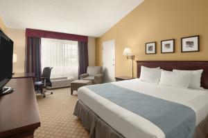 スーフォールズにあるCountry Inn & Suites by Radisson, Sioux Falls, SDの大型ベッドとテレビが備わるホテルルームです。