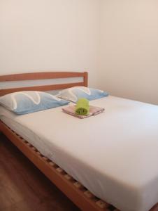 a bed with two pillows and a green hat on it at Apartman Mare in Kaštela