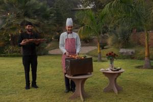 a man in a chefs hat holding a tray of food at SaffronStays Sylvan Farms - 3BR eco-luxury villa with birdwatching, trekking and organic farming in Mount Abu in Delmāra
