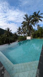 a large swimming pool with palm trees in the background at The Jungle Villa, Lombok in Mangsit