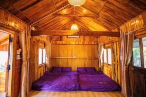 a bed in the inside of a wooden cabin at Sky Garden Moc Chau in Mộc Châu