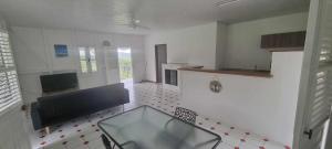 a kitchen with a glass table in the middle of a room at Haut de villa 1chambre climatisée à 3min de l'habitation Clément in Le François