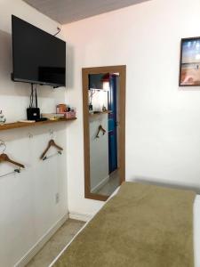 a room with a flat screen tv and a mirror at Suíte Colorida em Cabo Frio in Cabo Frio