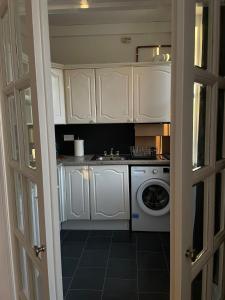Una cocina con gabinetes blancos y lavadora. en Cozy flat in the heart of Leith, en Edimburgo