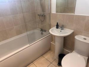 a bathroom with a sink and a tub and a toilet at Top floor 2 bedroom retreat in Morley