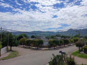 an empty street with trees and mountains in the background at Rincón SierraVista in Cosquín