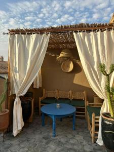 patio con panca, tavolo e tende di Riad bab Adam a Marrakech