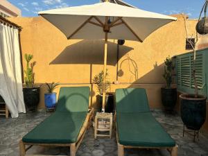 2 sedie e un ombrellone su un patio di Riad bab Adam a Marrakech