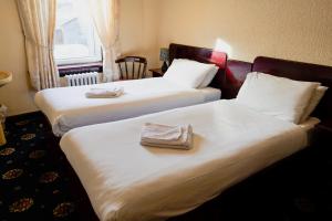 twee bedden in een hotelkamer met handdoeken erop bij Station Hotel Larbert in Falkirk