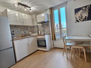 a kitchen with white appliances and a table and chairs at Nid Douillet au Bord du Canal #D in Chelles