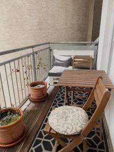 a balcony with a wooden table and chairs and plants at Urban Hotspot Apartment in Vienna
