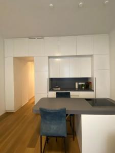 a kitchen with white cabinets and a table and a blue chair at Urban Hotspot Apartment in Vienna +7 photos