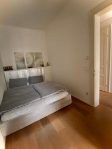 a bed in a white bedroom with a wooden floor at Urban Hotspot Apartment in Vienna